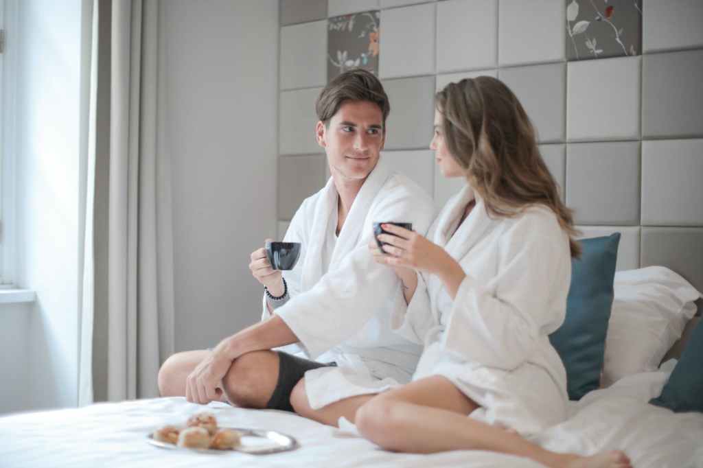 A couple wearing robes and drinking coffee at a bed-and-breakfast.
