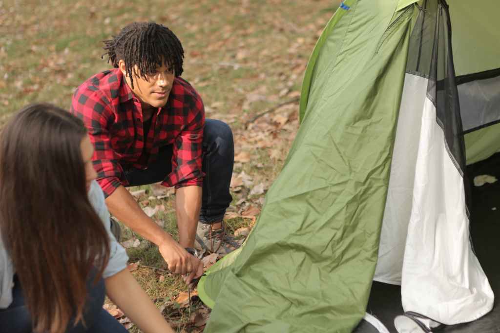 A couple pitch a tent on a camping trip.