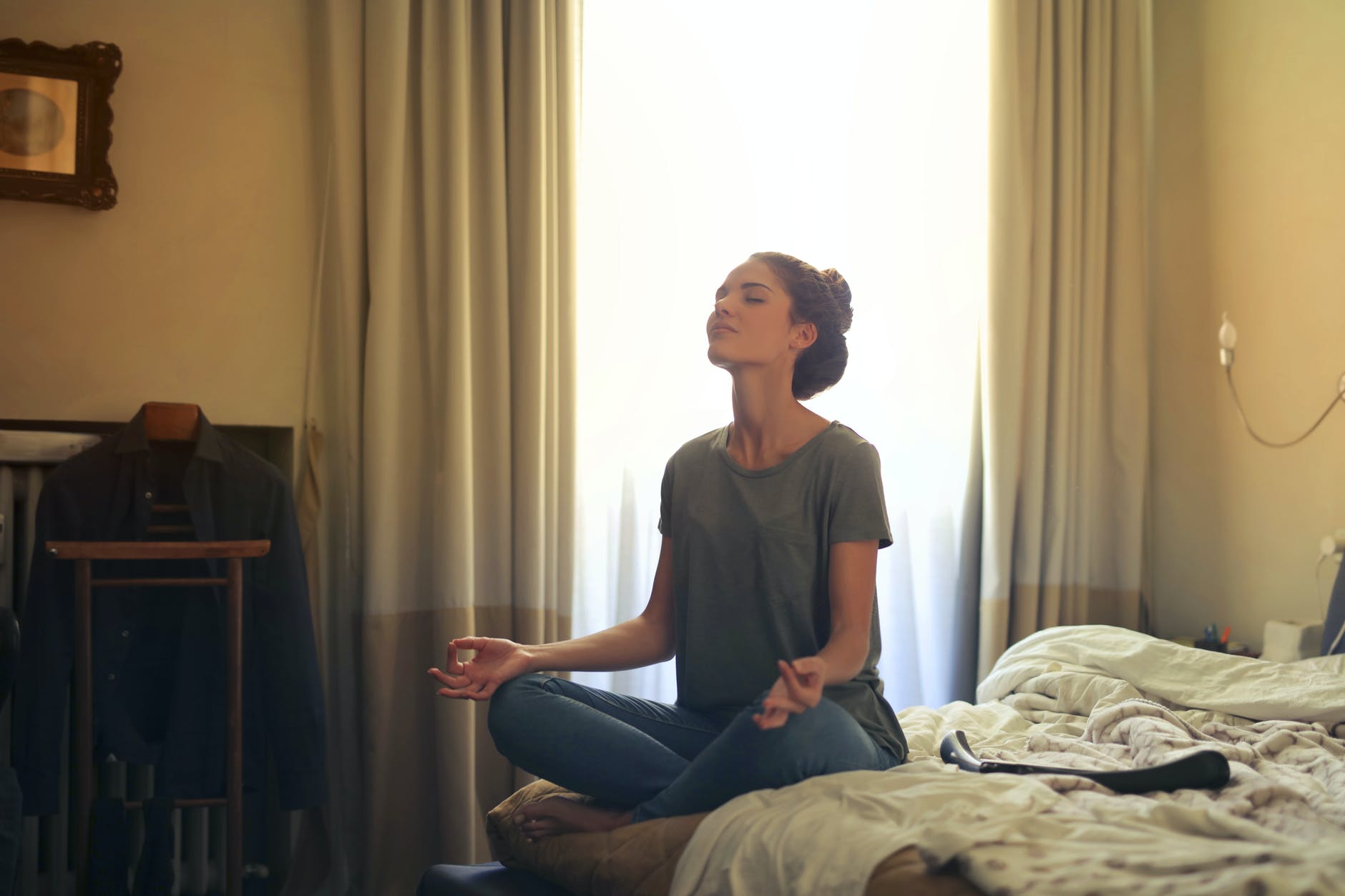Young woman meditates about her goals alone in her bedroom.